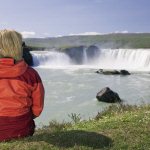 Vrouw kijkt uit over de Godafoss waterval